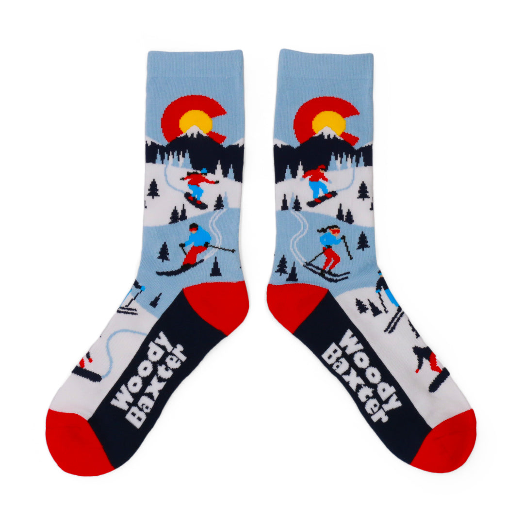 Pair of Adult CO Alpine Socks with a Colorado C above a snowy mountain scene with skiers and trees, with red toes and black feet.